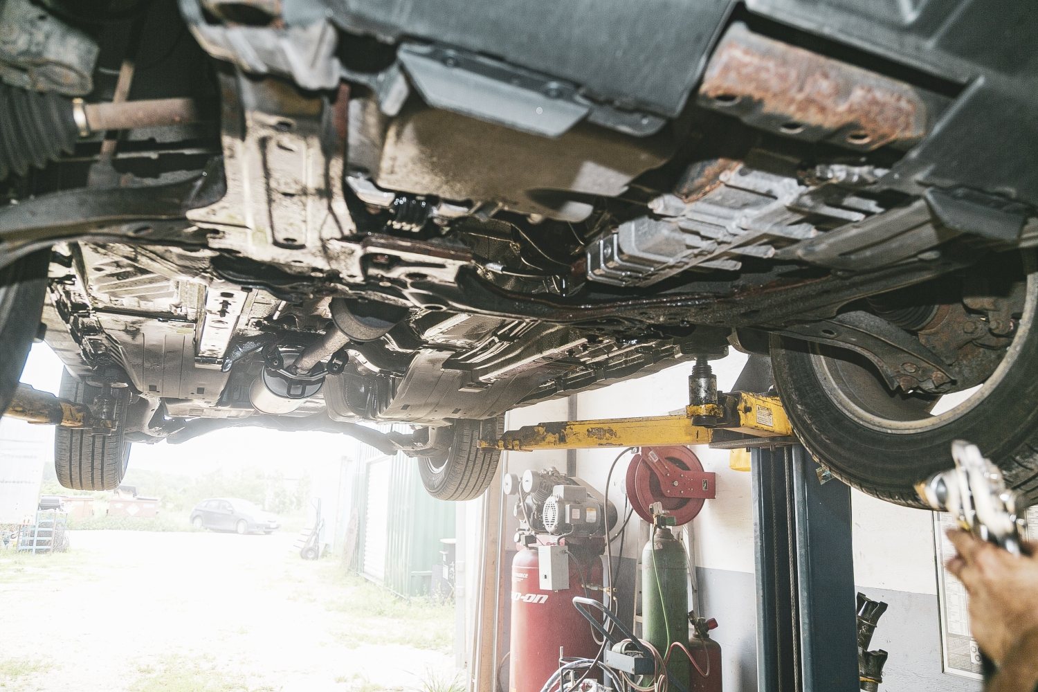 A view of a vehicle’s underside on the lift at Auto Solve, including plastic shields