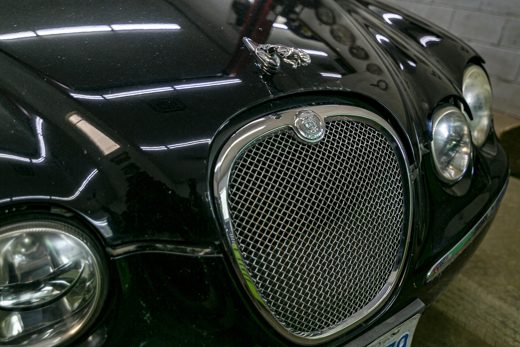 Gleaming black Jaguar grille and restored clear headlights — reconditioning that makes an older vehicle look better than new