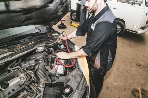 Technician testing a circuit under the hood with a test light