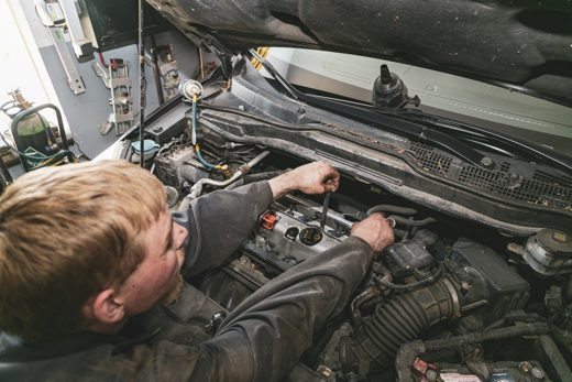 Auto Solve mechanic working under the hood on an engine in the Creemore service bay