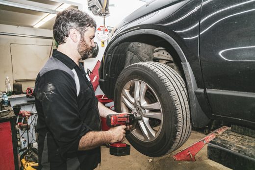 Mechanic torquing a wheel back onto a vehicle with a cordless impact wrench