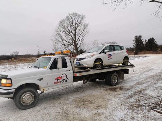 Auto Solve flatbed tow truck carrying a car in the snow