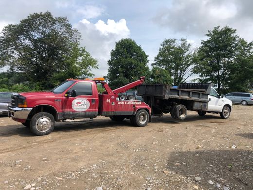 Red Auto Solve wrecker towing a dump truck